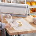 A person in a white apron using Choice wet wax paper to wrap a sandwich.