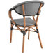 A Lancaster Table & Seating black and white wicker arm chair with a wooden frame and black and white seat.