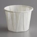 A white Genpak paper souffle cup with a white rim on a gray surface.