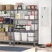 A gray Metro mobile wire shelving unit in a school kitchen with food items on it.