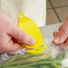 A person using a yellow CrewSafe Viper Pro bag opener to cut a plastic bag.