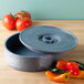 A round blue HS Inc. polyethylene container with a lid open next to tomatoes.
