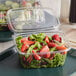 A salad in a Dart tamper-evident plastic container on a counter.