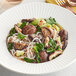 A white plate of noodles with Dried Whole Shiitake Mushrooms.