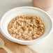 A bowl of Kodiak Cakes cinnamon oatmeal with a spoon on a table.