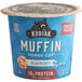 A blue Kodiak Cakes Blueberry Minute Muffin container on a table with a blueberry muffin inside.