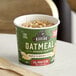 A green container of Kodiak Cakes Maple and Brown Sugar Oatmeal on a table.