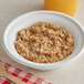 A bowl of Kodiak Cakes maple and brown sugar oatmeal with a wooden spoon.