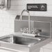 A stainless steel deck-mounted faucet with 4-inch centers and a 6-inch swivel gooseneck spout installed on a commercial sink.