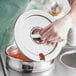 A person in gloves holding a Choice Deluxe Soup Marmite chafer cover over a pot.