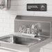 A stainless steel deck-mounted faucet with 4-inch centers and a 6-inch swing spout installed on a commercial sink.