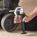 A hand using a Core Gear mini pistol grip grease gun to dispense grease.