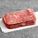 A stack of Original Philly Cheesesteak Co. marinated beef sandwich steaks on a white surface.