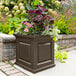 An espresso Mayne Nantucket planter with flowers on an outdoor table.