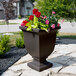 A Mayne espresso planter with flowers on an outdoor patio table.