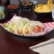 An oval bowl of tacos on a table in a Mexican restaurant.