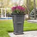 A Mayne Fairfield graphite gray planter with pink flowers in it.