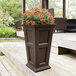 A large brown Mayne Fairfield planter with orange flowers.