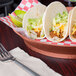 A table with a HS Inc. paprika deli server holding a plate of tacos with meat and vegetables.