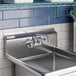 A stainless steel wall mount faucet with an 8-inch swing spout and 4-inch centers installed above a commercial sink.