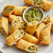 A plate of fried Southwest Chicken Egg Rolls with a small bowl of sauce.