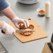 A person cutting a sandwich on a Mercer composite cutting board.