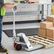 A man standing next to a Lavex galvanized steel pallet jack.