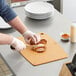 A person using a Mercer composite cutting board to cut a sandwich.