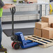 A man standing next to a Lavex pallet jack holding a box.