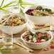 A table with bowls of salad, food, and a Solia white sugarcane pulp mix bowl with salad and chopsticks.