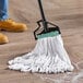 A person using a Rubbermaid white blend looped end wet mop with a handle to clean the floor.