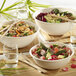 Solia white sugarcane pulp bowls filled with salad with chopsticks on a table.