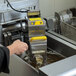 A person using a VITO fryer oil filtration machine to clean oil.