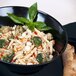 A bowl of pasta with broccoli and cheese in a black slanted melamine bowl.