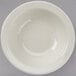 A Tuxton Reno narrow rim china monkey dish with a curved edge on a gray surface.