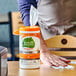 A person's hand using Seventh Generation Lemongrass Citrus Disinfecting Wipes to clean a table.