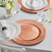 A table set with Choice rose gold charger plates and glasses.