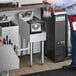 A man standing at a stainless steel Regency blender station with a drink.