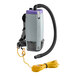 A ProTeam backpack vacuum with a hose attached.