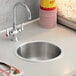 A Regency stainless steel sink with a container of popcorn.