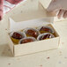 A hand holding a gold linen candy box filled with chocolates.