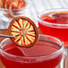 A slice of Cocktail Garnish dried blood orange in a glass of red liquid.