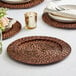 A table set with Acopa Brunet rattan charger plates, utensils, and glasses.