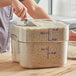 A person using a spatula to scoop rice into a Cambro CamSquares container.