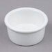A Tuxton white china ramekin on a gray surface.