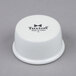 A white Tuxton china ramekin with black text.