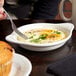 A bowl of eggs with a Tuxton white shirred egg dish and fork.