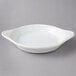 A white round Tuxton shirred egg dish with handles.