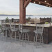 A group of Holland Bar Stool stainless steel slat back swivel counter stools on an outdoor patio counter.