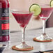 A glass of Twisted Alchemy Pomegranate juice with lime slices on top.